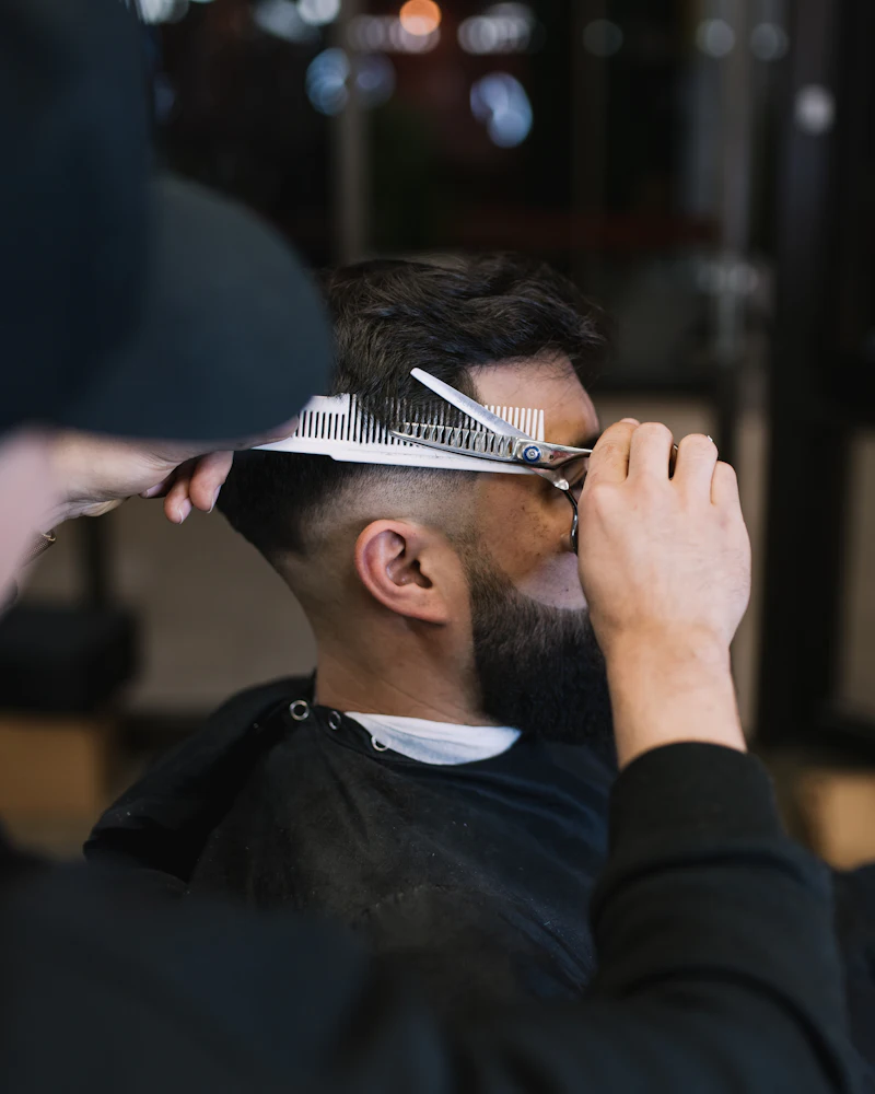 Davie cutting a client's hair with scissors and comb