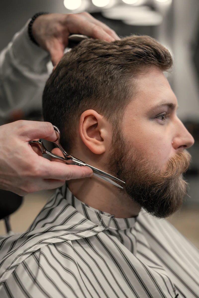 Sami trimming a client's beard with scissors