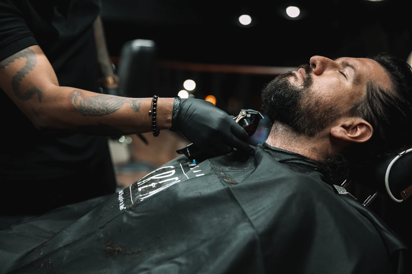 A client leaning back while his beard is lined up with clippers
