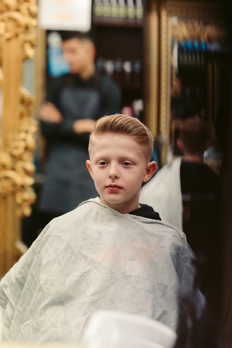 A young boy in a barber's cape after his haircut
